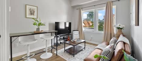 En moderne stue med sofa, sofabord, fjernsyn og barstole.
