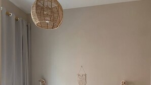 Une chambre à coucher avec un lit, un luminaire suspendu, une décoration murale en macramé et une table de chevet avec une lampe.