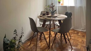 Un coin repas avec une table ronde, des chaises, un luminaire suspendu et des œuvres d’art encadrées accrochées au mur.