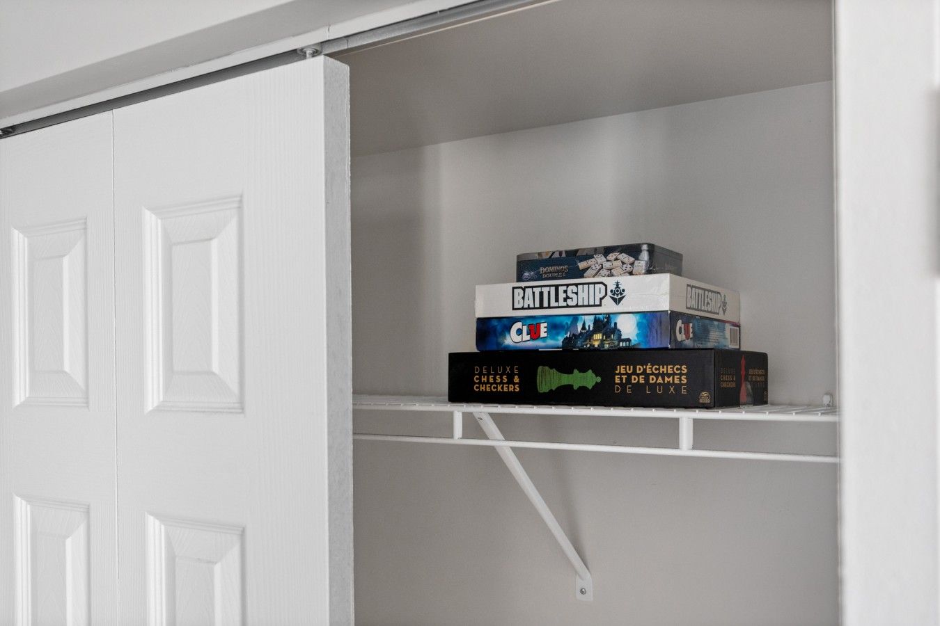 A white closet with a shelf holding board games.