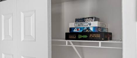 A white closet with a shelf holding board games.