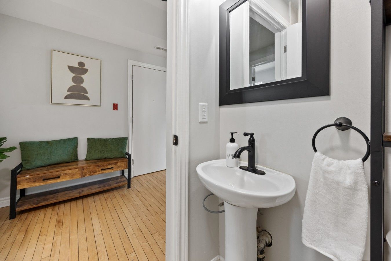 A bathroom with a white sink, black faucet, and a towel ring.