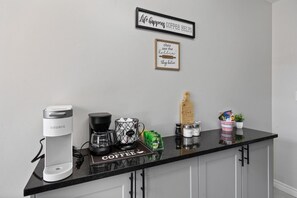 A kitchen counter with a Keurig coffee maker, a coffee grinder, and a coffee-themed sign. - 4 Bedrooms, 3 Kitchens & 3 Bathrooms—Perfect for Groups (Windsor)