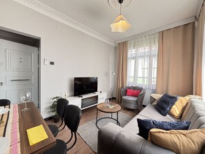 Ein modernes Wohnzimmer mit Fernseher, Sofa und Essbereich.