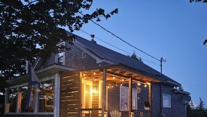 Ein Holzhaus mit Veranda, Treppe und einer Flagge.
