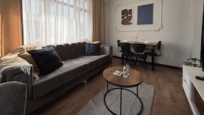 Ein modernes Wohnzimmer mit einer Couch, einem Esstisch, Stühlen und einem Couchtisch.