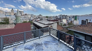 Eine Dachterrasse mit Blick auf eine Stadtlandschaft, darunter Gebäude und ein Turm.