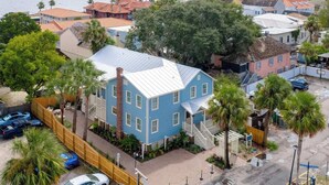 Zona residencial costera con una casa azul destacada, con un porche blanco y una chimenea de ladrillo.