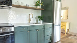 Una cocina con gabinetes verde azulado, un refrigerador de acero inoxidable y un horno empotrado.