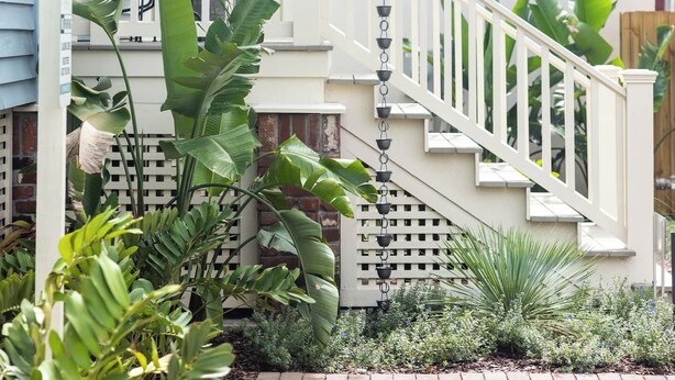 Et hus med veranda, trappe og mange planter.