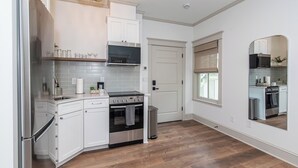 Eine moderne Küche mit weißen Schränken, einem Edelstahlkühlschrank, einem Einbauofen und einer Mikrowelle.