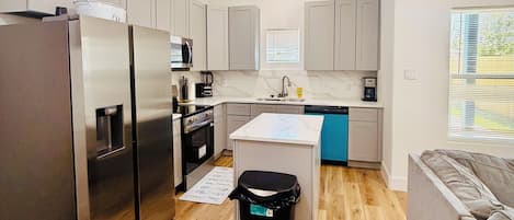 A modern kitchen with stainless steel appliances, a central island, and a built-in oven.