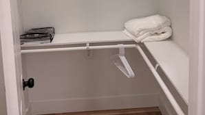 Et hvidt skab med bøjlestang, en hylde og et foldet håndklæde.