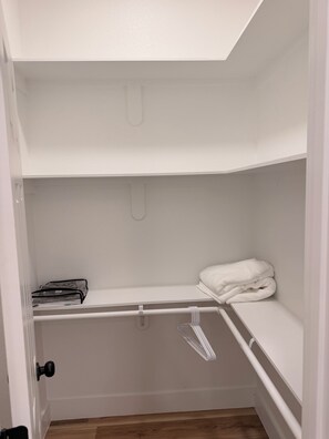 Ein weißer Kleiderschrank mit Kleiderstange, Ablagefläche und gefaltetem Handtuch.