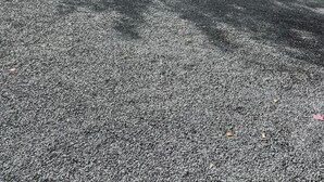 Une terrasse avec des sièges extérieurs, une clôture en bois et un sol en gravier.