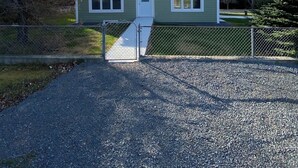 Une maison de plain-pied avec une porte d’entrée, un petit porche et une allée gravillonnée.
