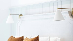 A bed with white bedding, two brown pillows, and a white headboard.
