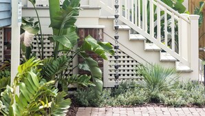 A house with a white porch, a staircase, and a garden with various plants. - Luxury Boutique Hotel | All 8 Suites | Sleeps 24 | Steps from St. George Street! (St. Augustine)