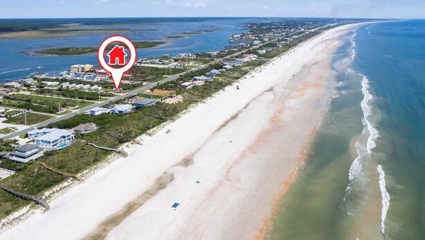 Luftaufnahme einer Küstenregion mit Strand, Häusern und einem Yachthafen.