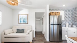 Eine moderne Küche mit einem Edelstahlkühlschrank, einem weißen Sofa und einem Holzessttisch.