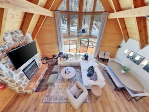 A spacious loft-style room with a stone fireplace, a large TV, and a cozy seating area with a sofa and chairs. - Fall in Brian Head means golden aspens, crisp mountain air & quieter trails. This 5-bedroom retreat pairs outdoor adventure with a hot tub, fire pit, chef’s kitchen, game room and restorative spaces for families, friends and multi-generational stay. (Brian Head)