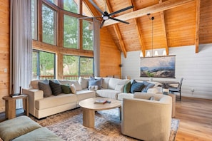 A spacious living room with a large sectional sofa, a coffee table, and a ceiling fan. - Fall in Brian Head means golden aspens, crisp mountain air & quieter trails. This 5-bedroom retreat pairs outdoor adventure with a hot tub, fire pit, chef’s kitchen, game room and restorative spaces for families, friends and multi-generational stay. (Brian Head)