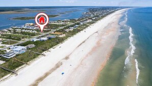 Luftaufnahme einer Küstenregion mit Strand, Häusern und einem Yachthafen.