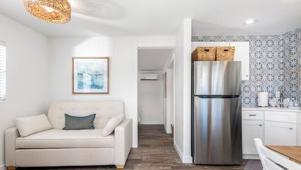 Eine moderne Küche mit einem Edelstahl-Kühlschrank, einem weißen Esstisch und einer Couch in einem Wohnbereich.