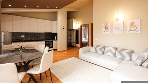 Uma sala de estar moderna com um sofá branco, uma mesa de jantar com cadeiras e uma área de cozinha com armários e fogão.