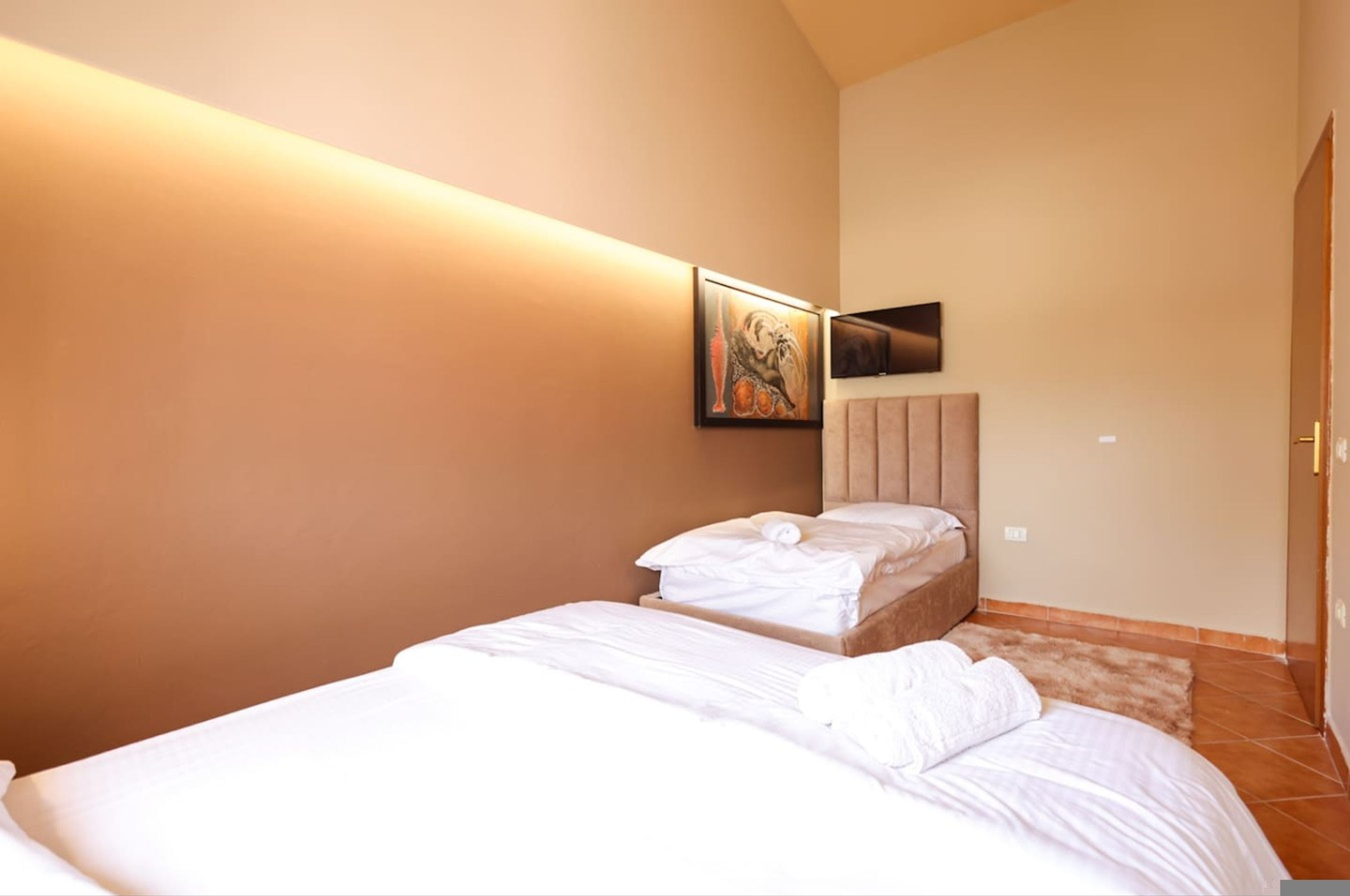 Une chambre à coucher avec un lit, un tableau, une télévision et une porte.