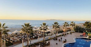 Un resort con mesas al aire libre, piscina y vista al mar.
