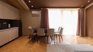 Une cuisine moderne avec un coin repas comprenant une table et des chaises, ainsi qu’une grande fenêtre avec des rideaux.
