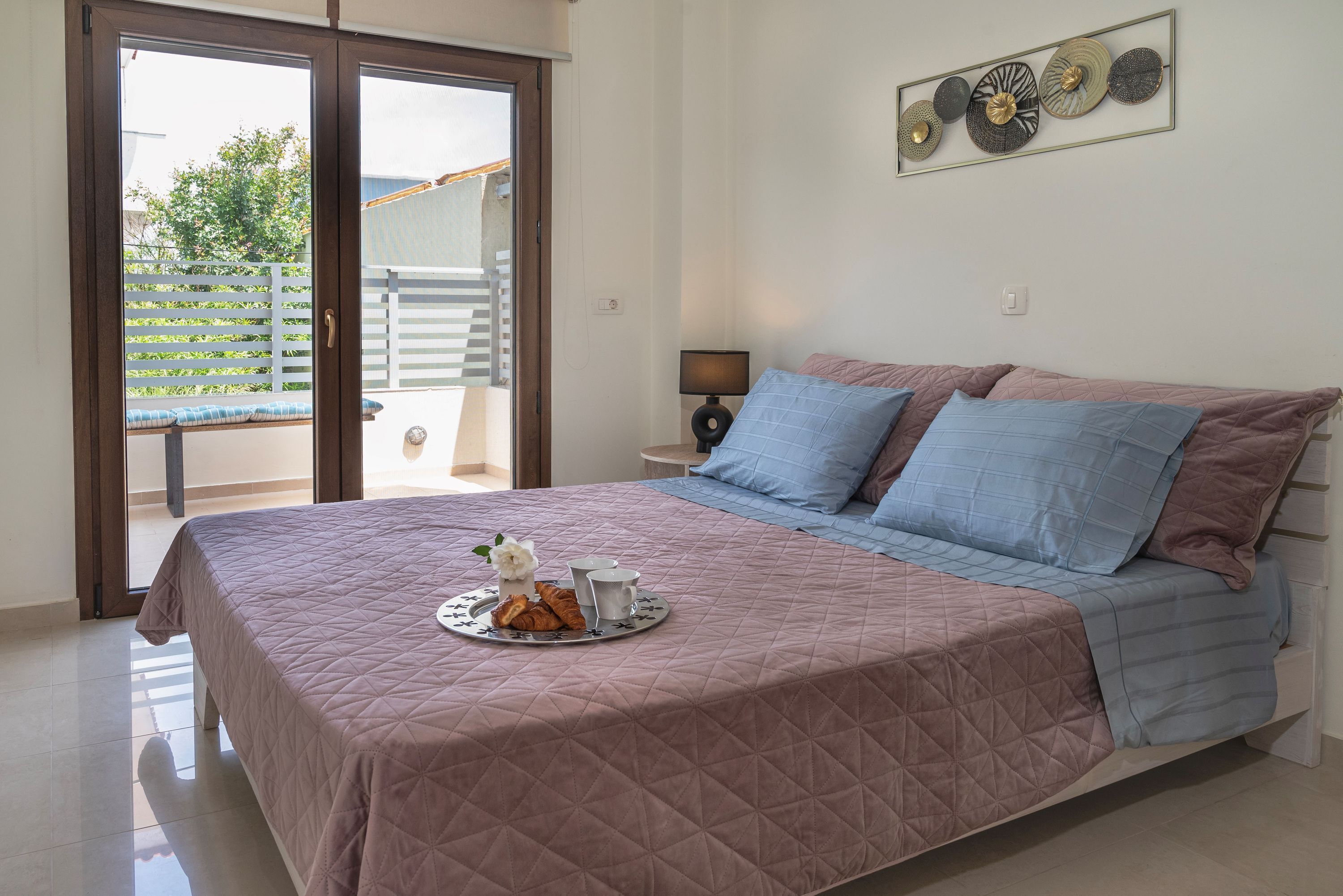 Une chambre avec un lit, un plateau de nourriture et une vue sur l’extérieur.