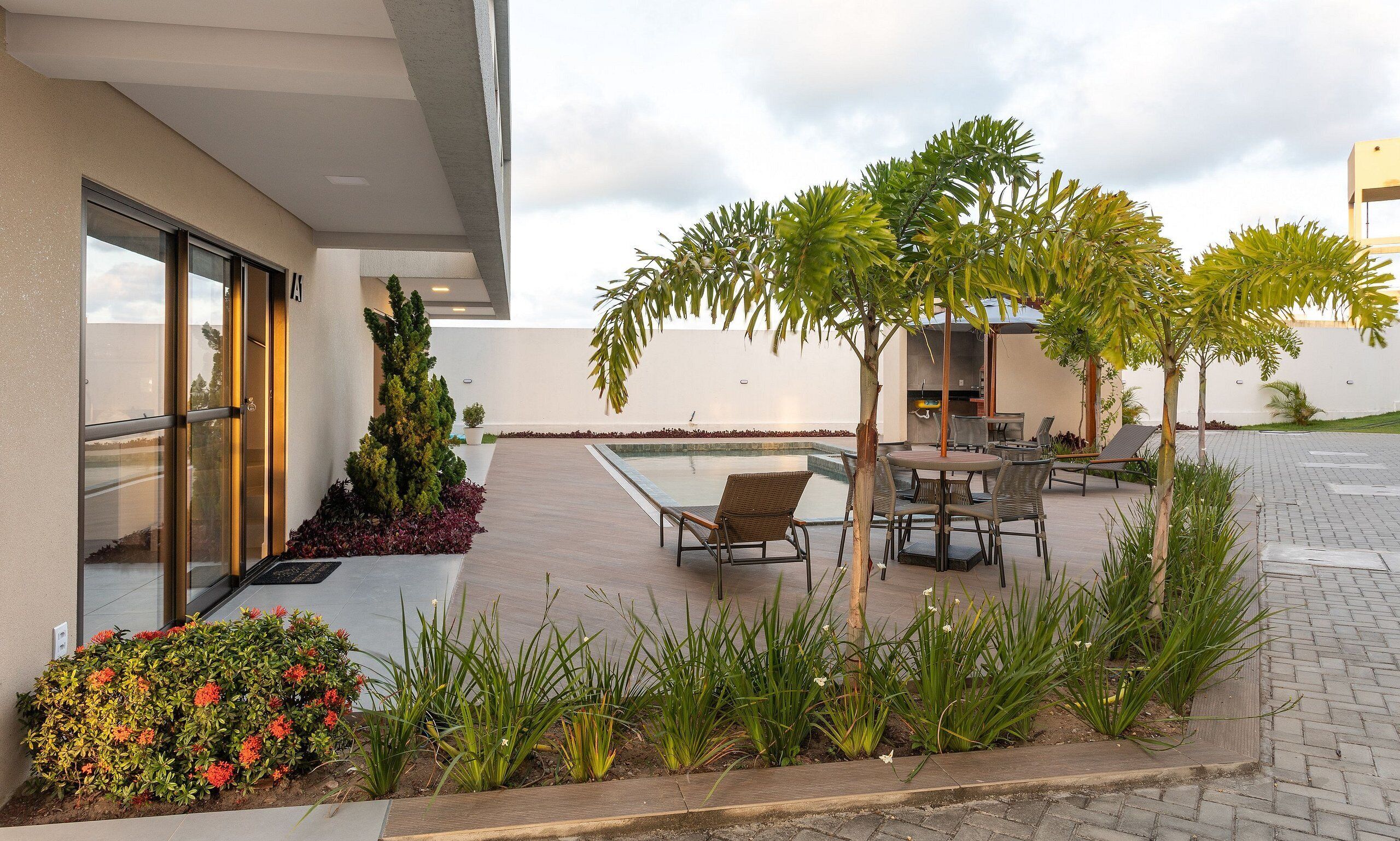 A modern outdoor area with a pool, seating, and a small garden.