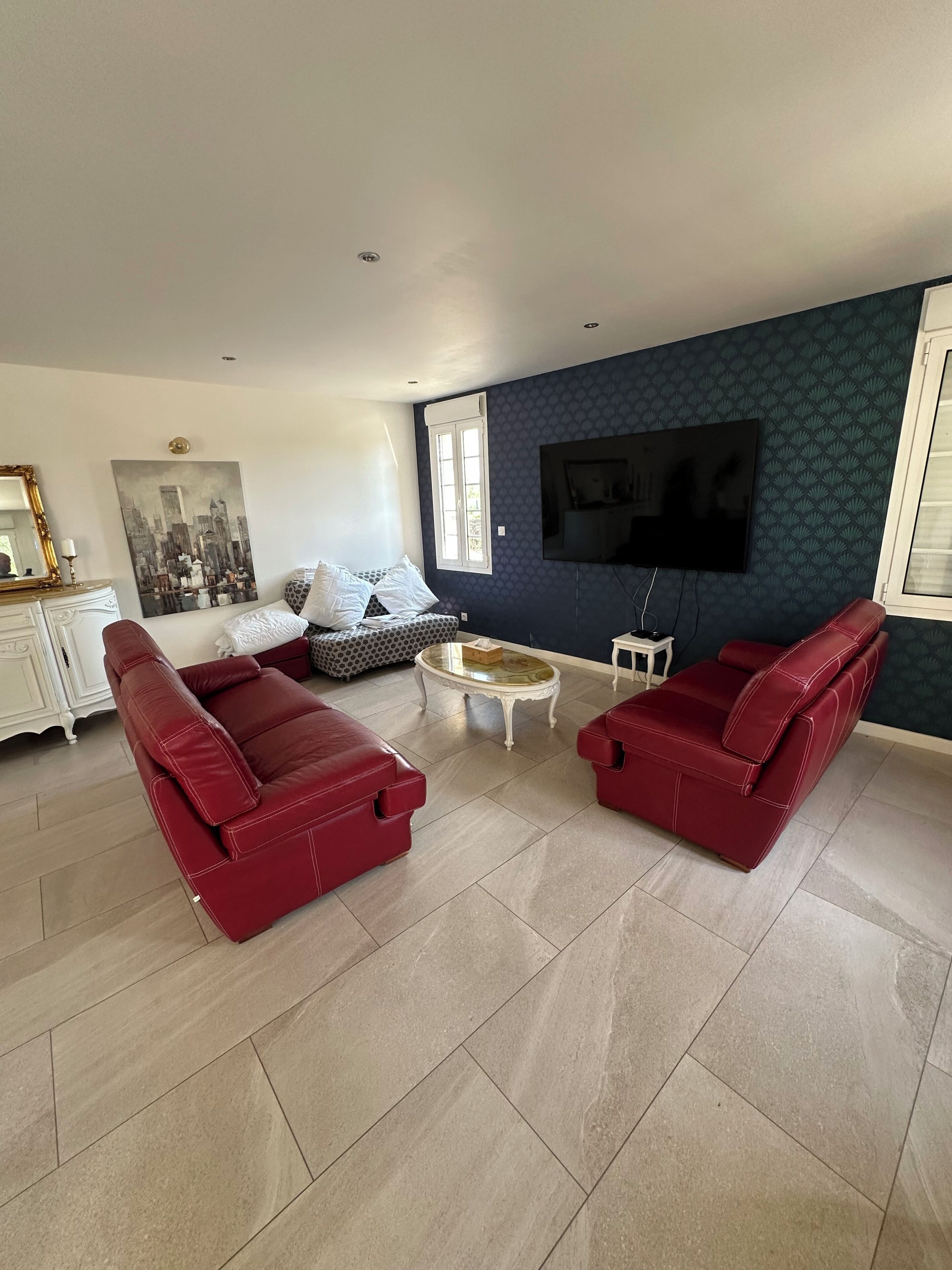 Un salon comprenant un ensemble de canapés, une table basse, un téléviseur et un mur décoré d’un motif.
