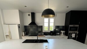 Una cocina moderna con una isla grande, electrodomésticos negros y una lámpara colgante.