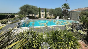 Una piscina rodeada de follaje y un edificio al fondo.
