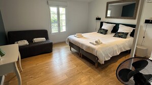 Un dormitorio con cama, escritorio, silla, ventilador de pie y ventana.