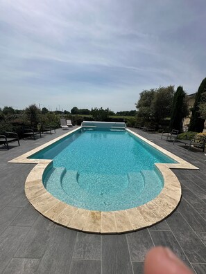 A rectangular swimming pool with a tiled edge, surrounded by a deck with chairs and a circular stone border. - Splendid contemporary villa amidst vineyards on the outskirts of Bordeaux (saint louis de montferrand)
