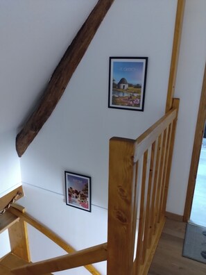 A staircase with wooden railings and a white wall with framed pictures.