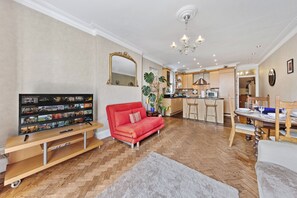 Ein Wohnzimmer mit Fernseher, einem roten Sofa, einer Holz-Unterhaltungsecke und einem Essbereich mit Tisch für vier Personen.