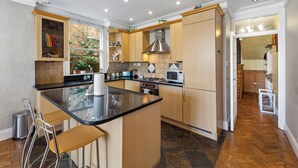 Een moderne keuken met een centraal eiland, houten kastjes en een inbouwmagnetron.