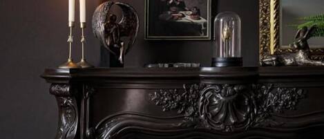 A fireplace with a dark mantel, a framed picture, and two lit candles.