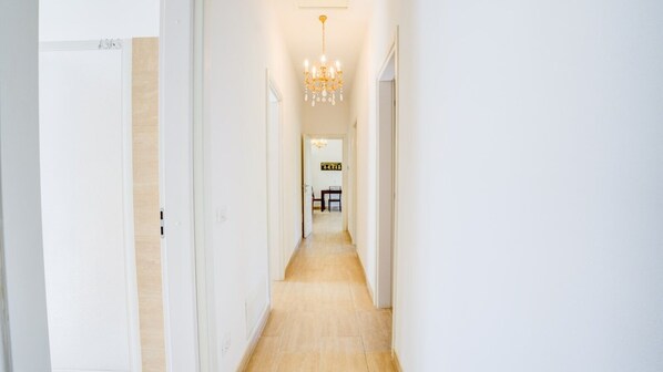 A hallway with a chandelier, white walls, and a wooden floor. - Bright villa 10 minutes from the beach and center of Forte dei Marmi (Forte dei Marmi)
