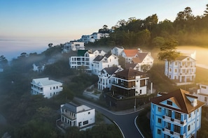 Ein Wohngebiet mit Häusern an einem Hügel, einer kurvenreichen Straße und blauem Himmel.