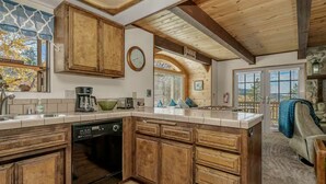 A kitchen with wooden cabinets, a dishwasher, and a large window. - Hot Tub, Near Bear Mt, Lake Views, Dog Yard, AC (Big Bear Lake)