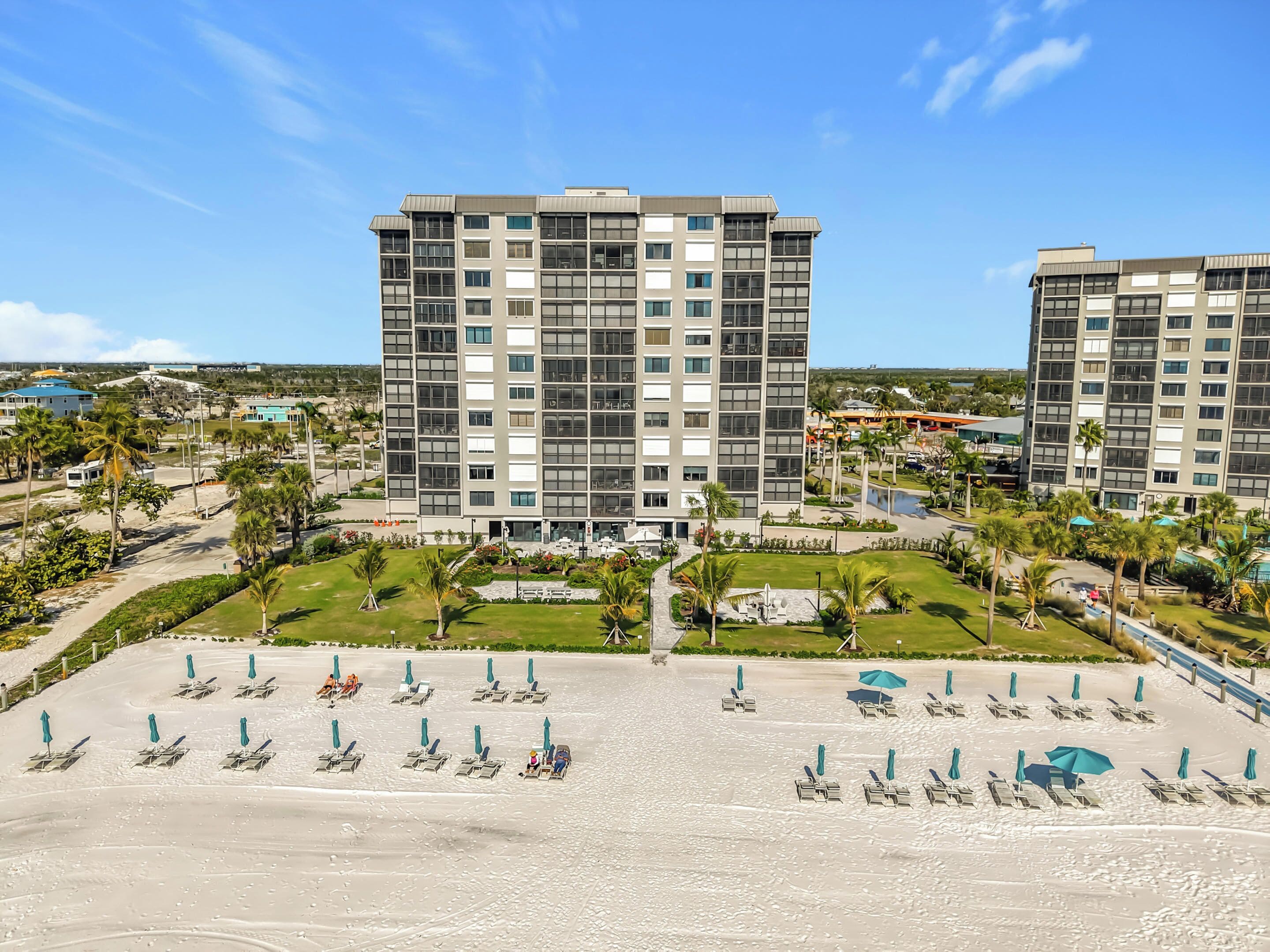 A hotel with multiple floors, a central courtyard, and a beach area with sun loungers.