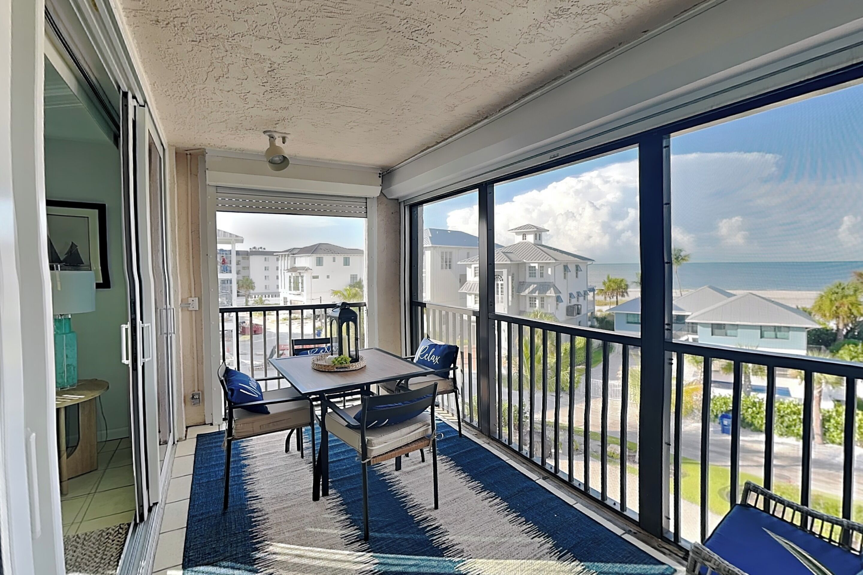 Un balcon avec une table et des chaises, une vue sur la mer et un bâtiment en arrière-plan.