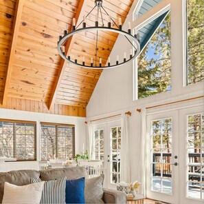 A room with a high wooden ceiling, large windows, a chandelier, and a cozy seating area. - Lakefront House With AC, Private Dock, Game Loft (Big Bear Lake)