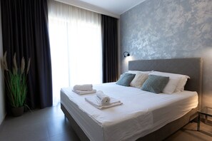 Ein modernes Hotelzimmer mit einem großen Bett, einem Kopfteil und einem Nachttisch.
